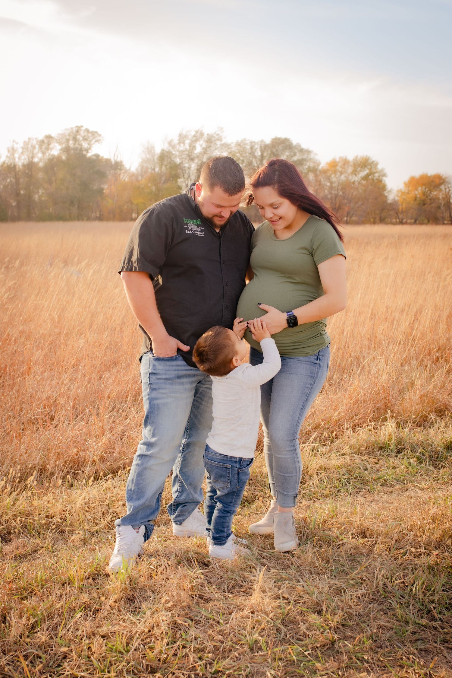 Family shares playful moment together in golden field at sunset.