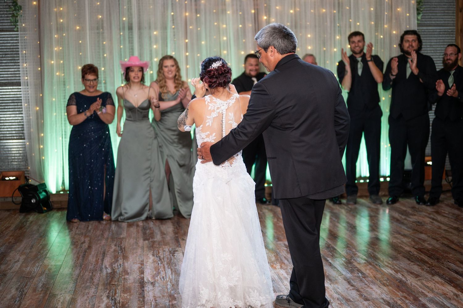 Couple shares a romantic dance moment with twinkling lights in the background.
