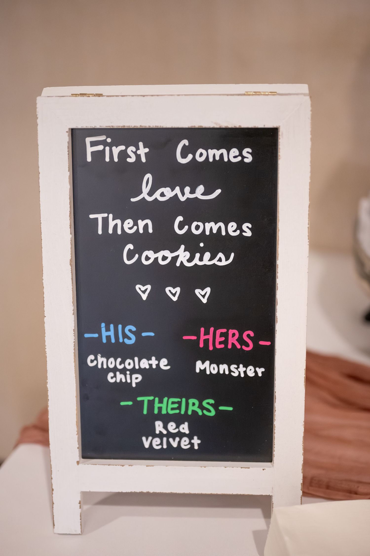 A chalkboard sign displaying cookie choices for His, Hers, and Theirs at a wedding reception.