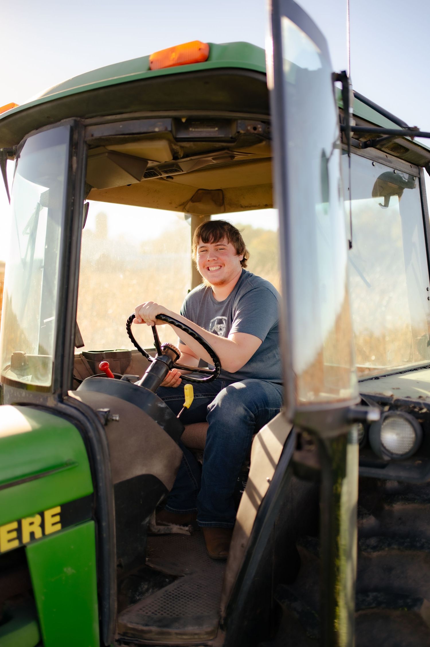 A series of shots showing someone operating a John Deere tractor during sunset in a rural setting.