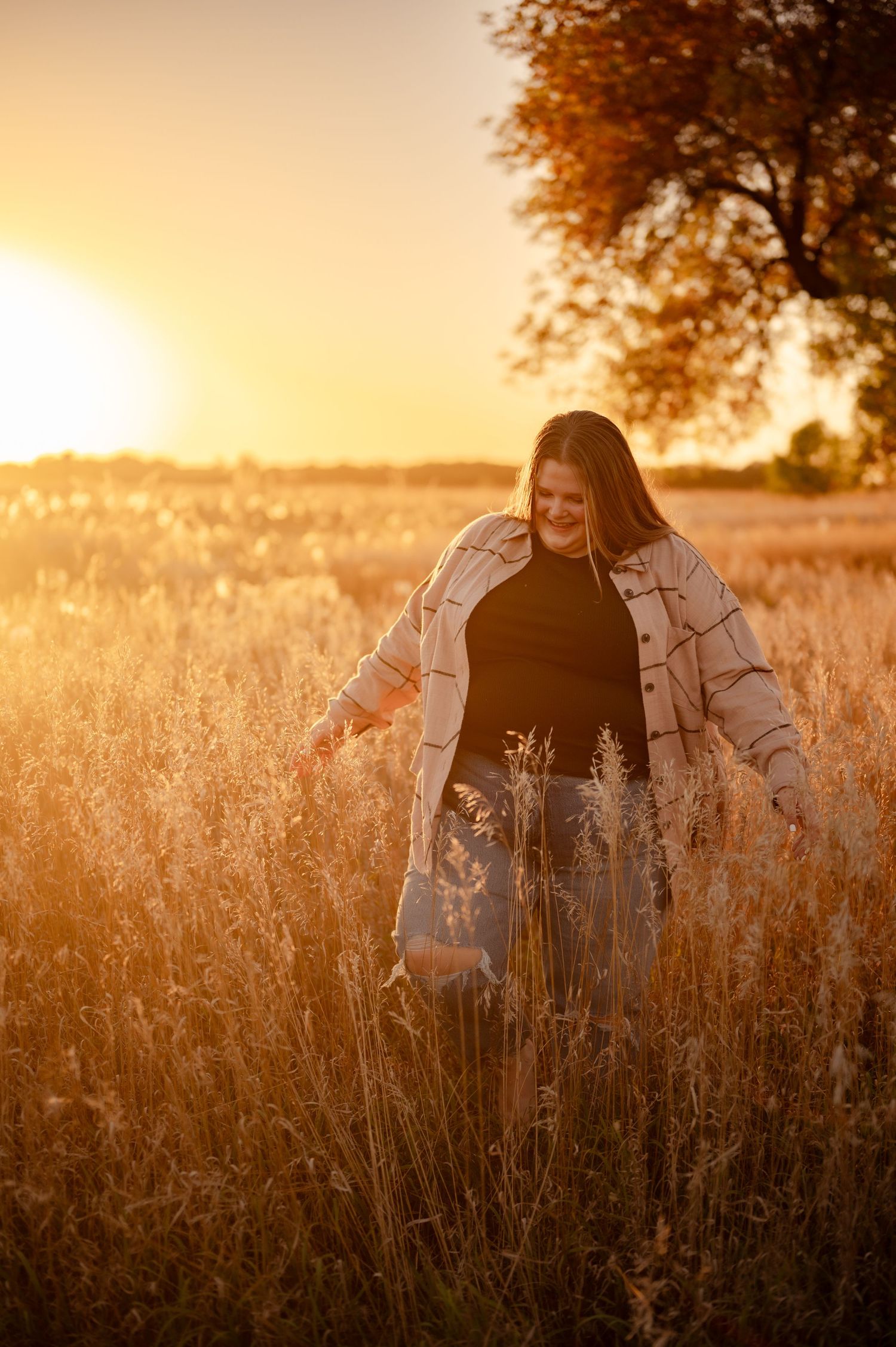 Golden hour portrait in a tall grass field with warm sunset lighting.