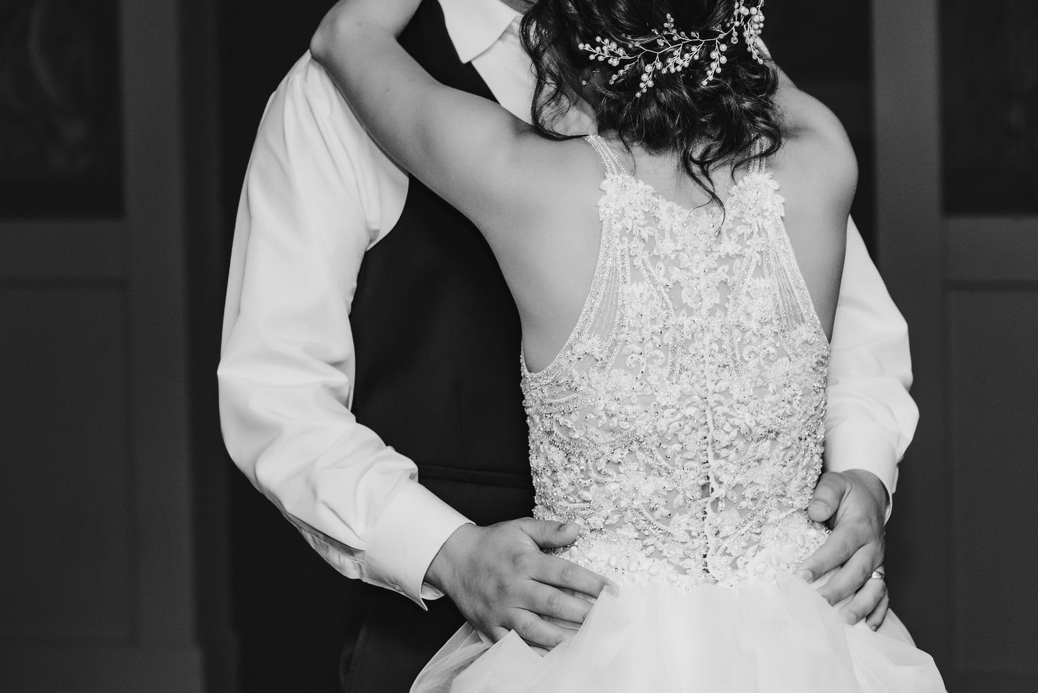 A black and white detail shot of a lace wedding dress during a dance.