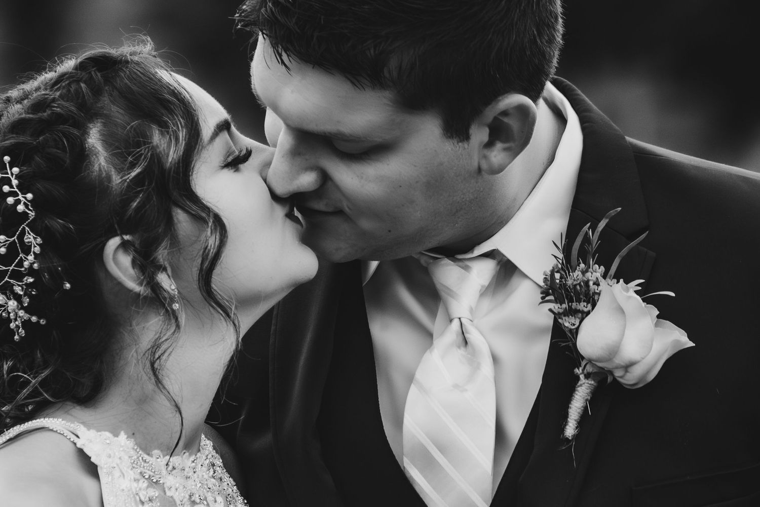 Black and white romantic wedding photograph of a bride and groom sharing a tender kiss.