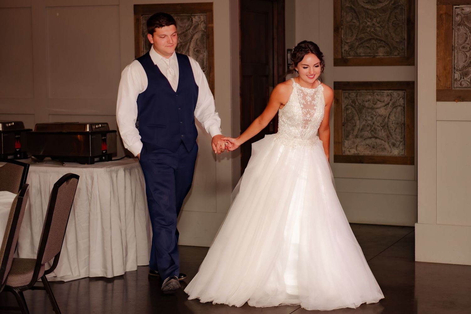 A couple dancing together in formal wedding attire on a polished ballroom floor.