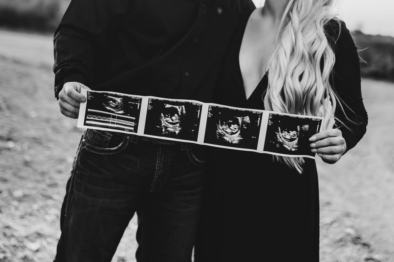 A series of ultrasound photos held up in sequence showing the progression of a pregnancy.
