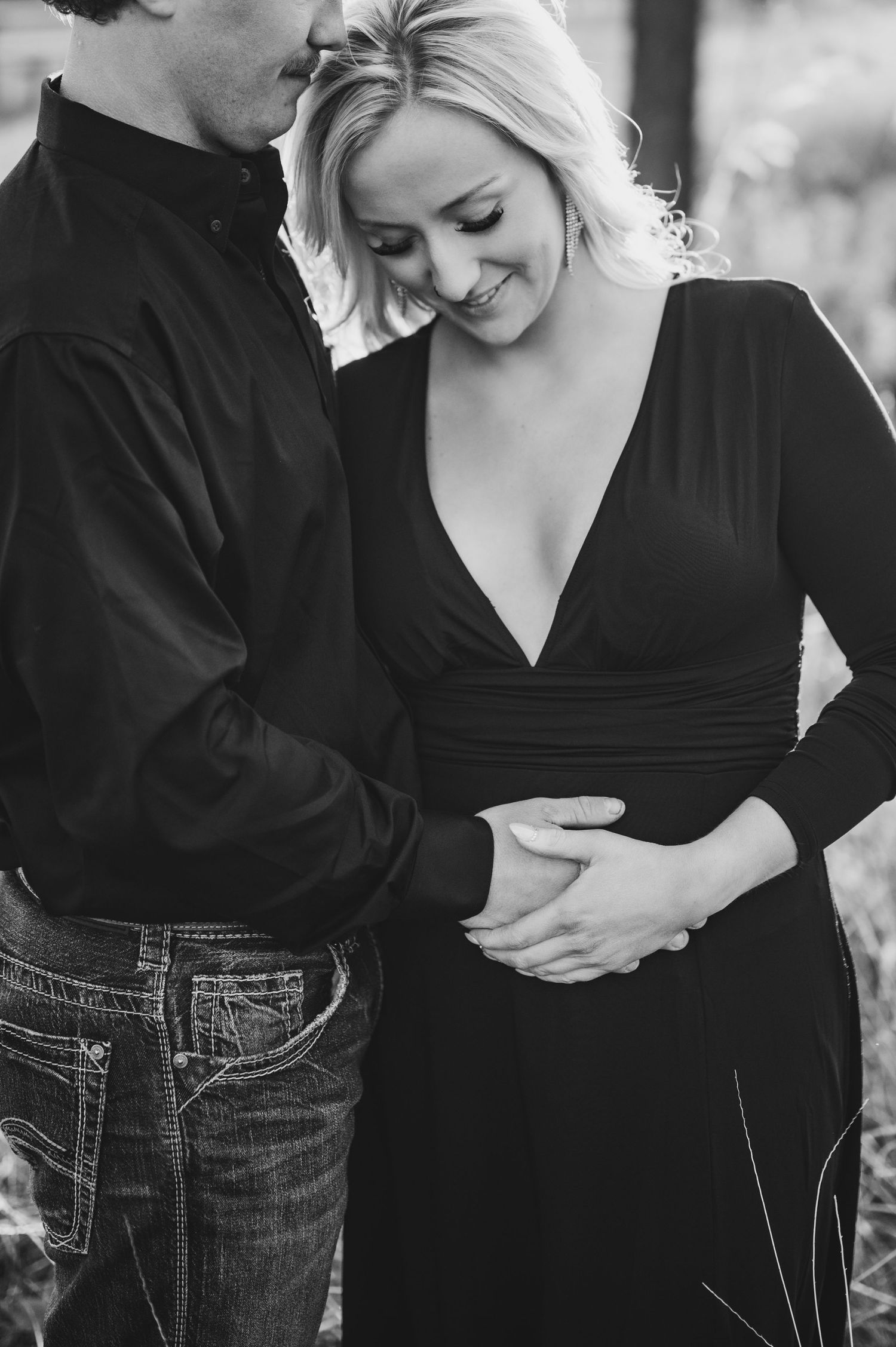 Black and white photo of couple sharing intimate moment outdoors in casual attire.