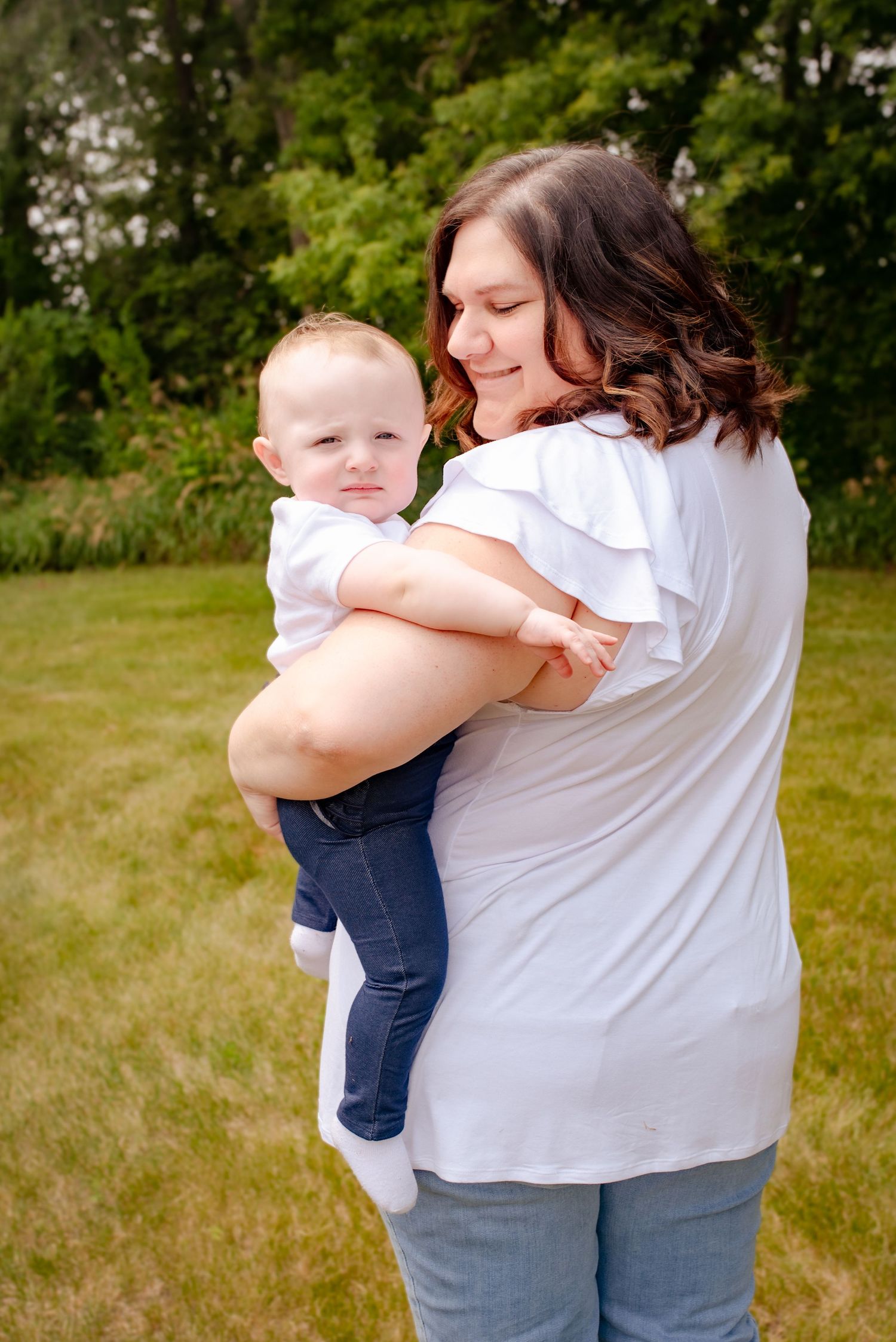 A tender moment between parent and baby captured outdoors in a natural setting.
