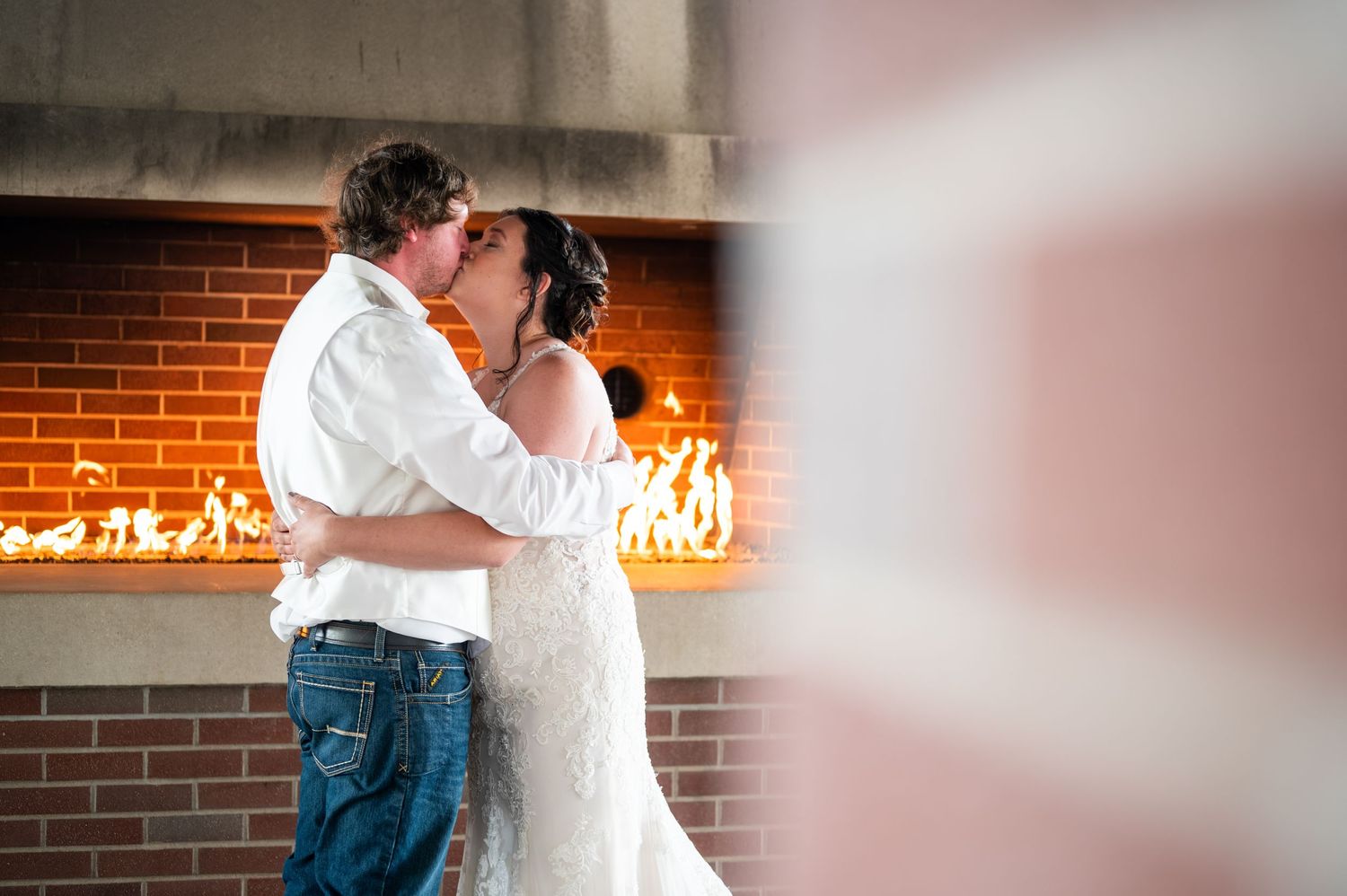 Romantic dance moment in front of glowing fireplace at wedding reception.