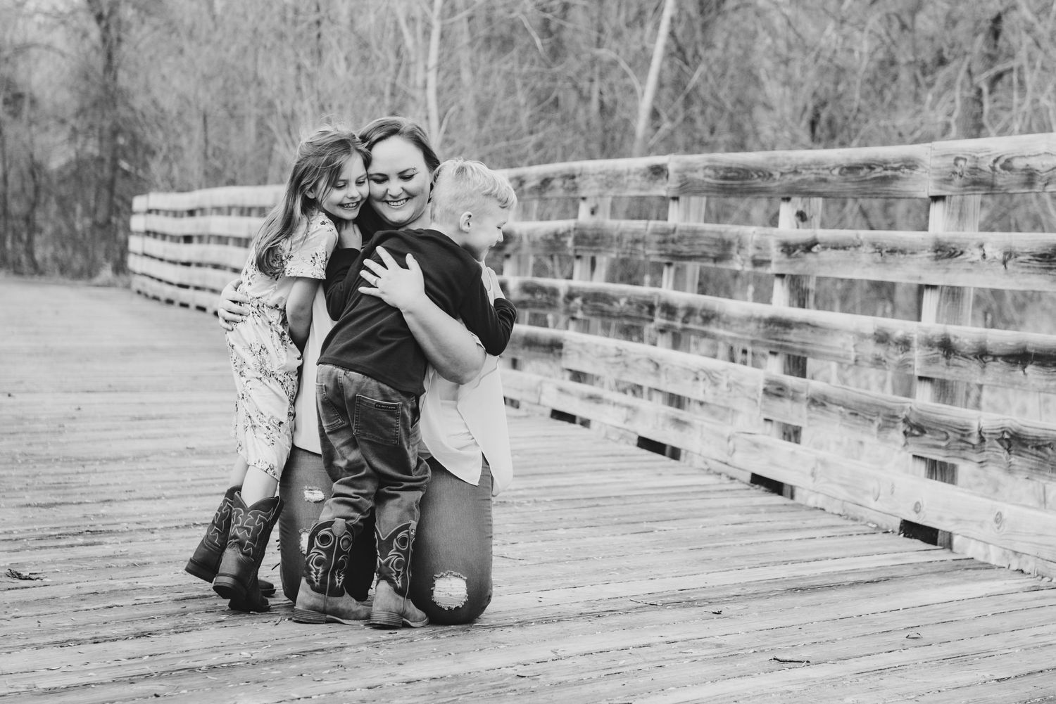Black and white photo of people sharing an intimate moment on a wooden boardwalk.