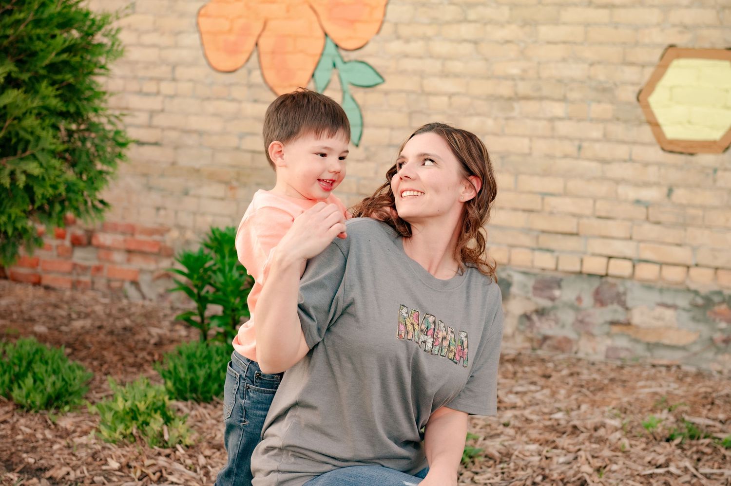 Candid family moment against brick wall with painted floral design.