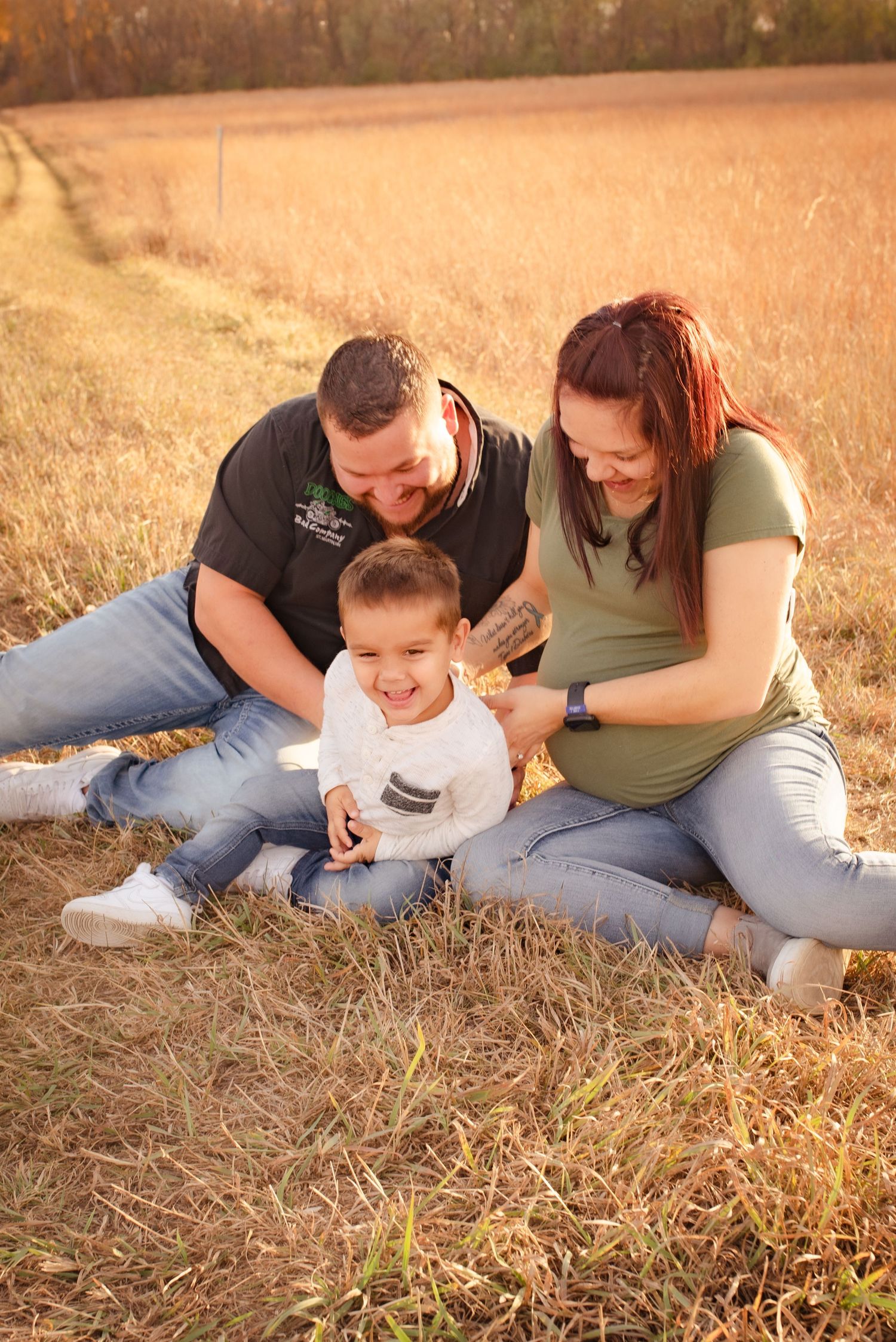 Family shares candid laughs while relaxing together in a golden autumn field at sunset.