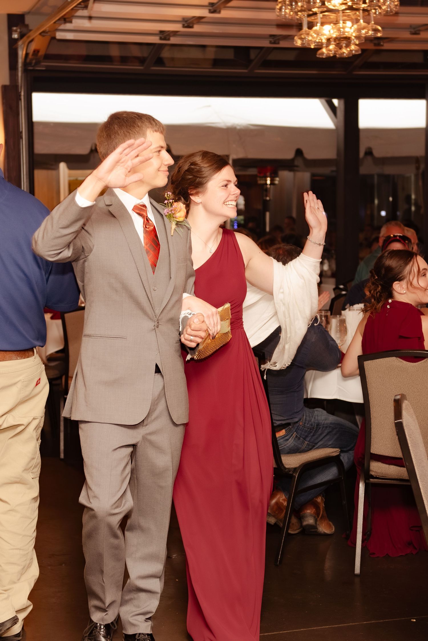 Wedding guests dancing and celebrating in formal attire at an indoor reception venue.