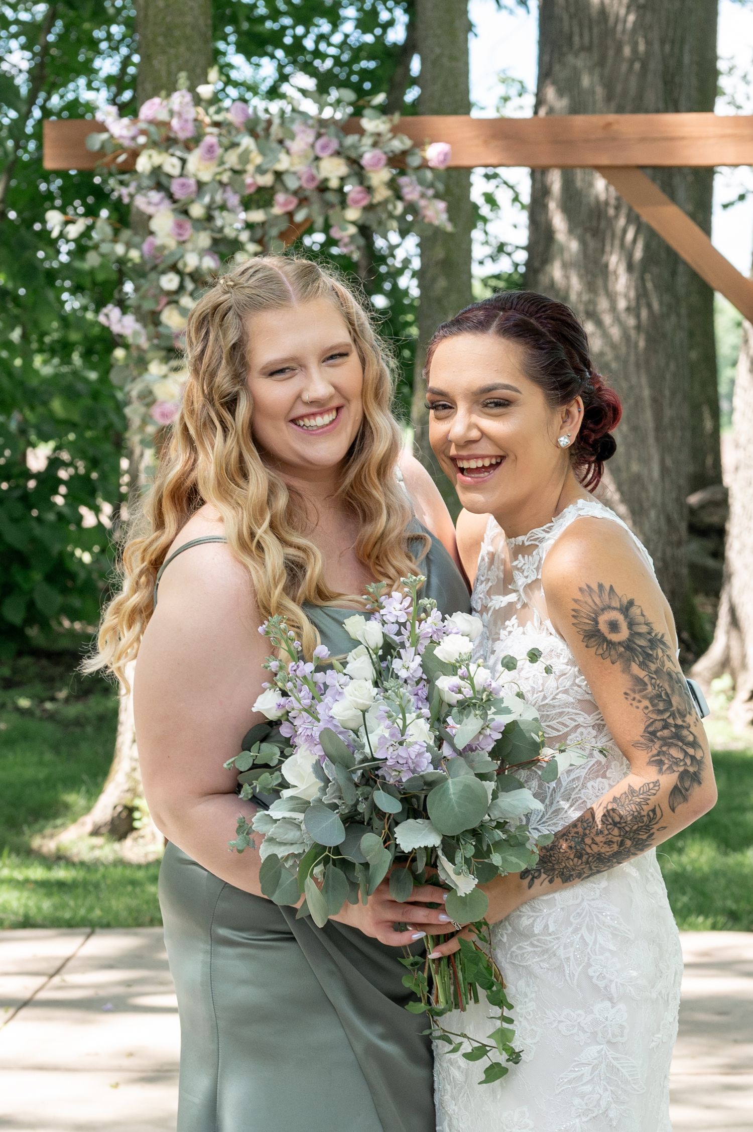 Wedding party members sharing a candid laughing moment while holding a beautiful floral bouquet.