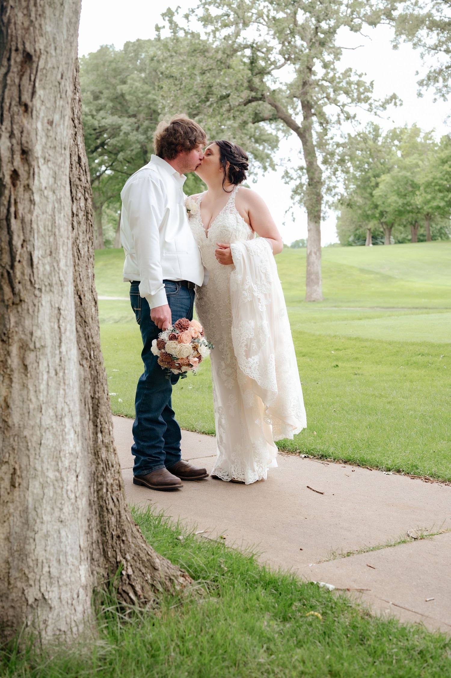 Romantic moment between couple on tree-lined pathway during wedding.