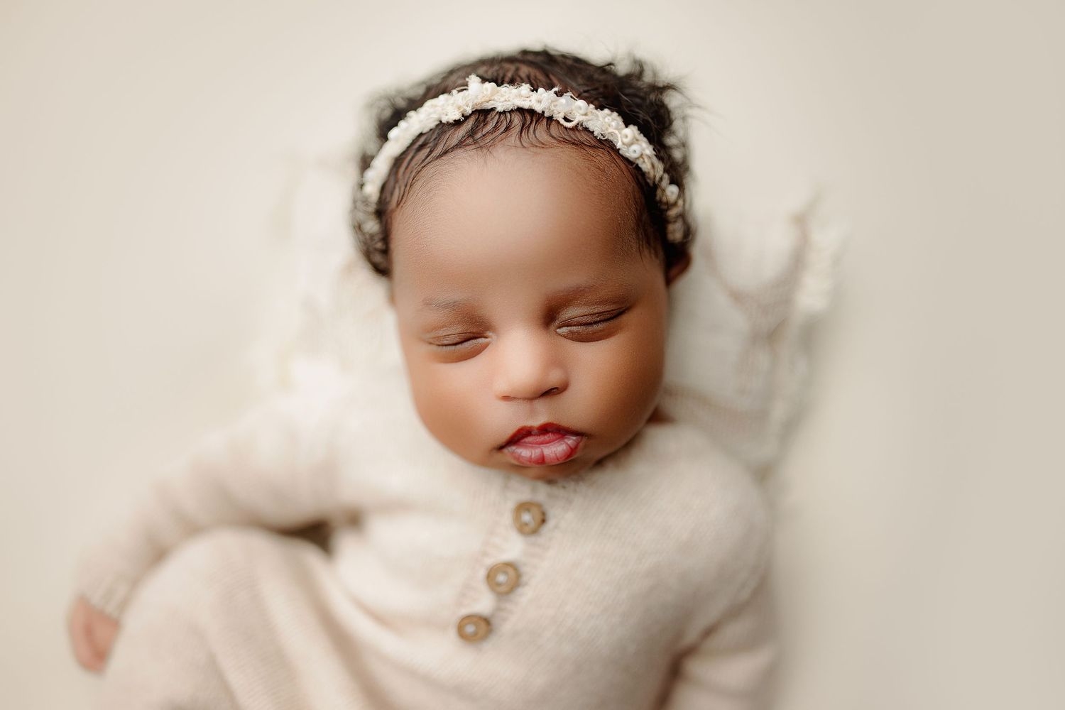 Timeless newborn portrait in Indianapolis featuring a baby girl posed on neutral background and with neutral knit outfit