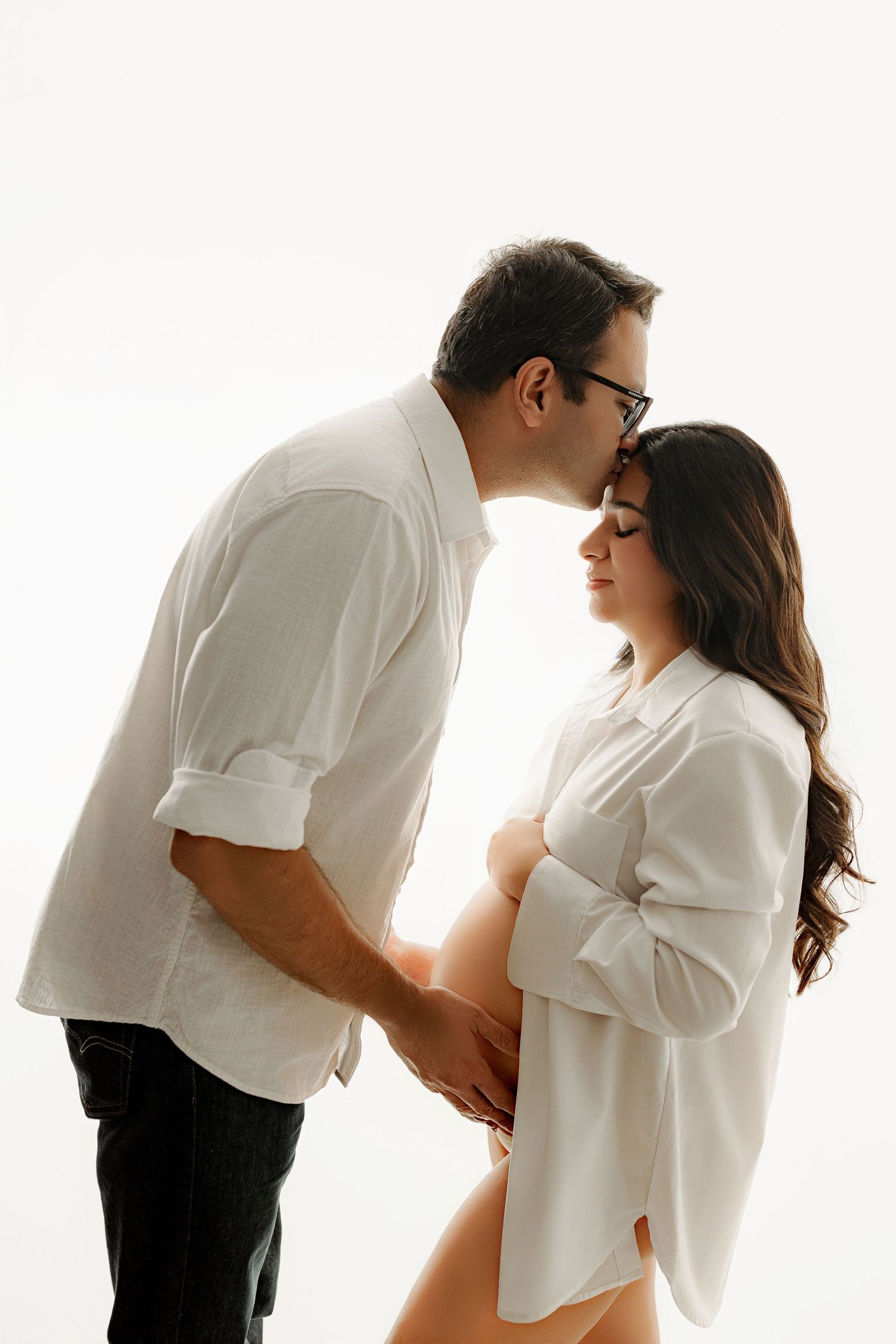 pregnant woman in a white shirt, belly exposed posed in indianapolis maternity studio