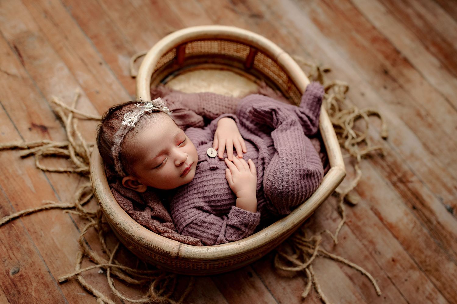 A baby sleeps peacefully in a heart-shaped basket during newborn session central Indiana