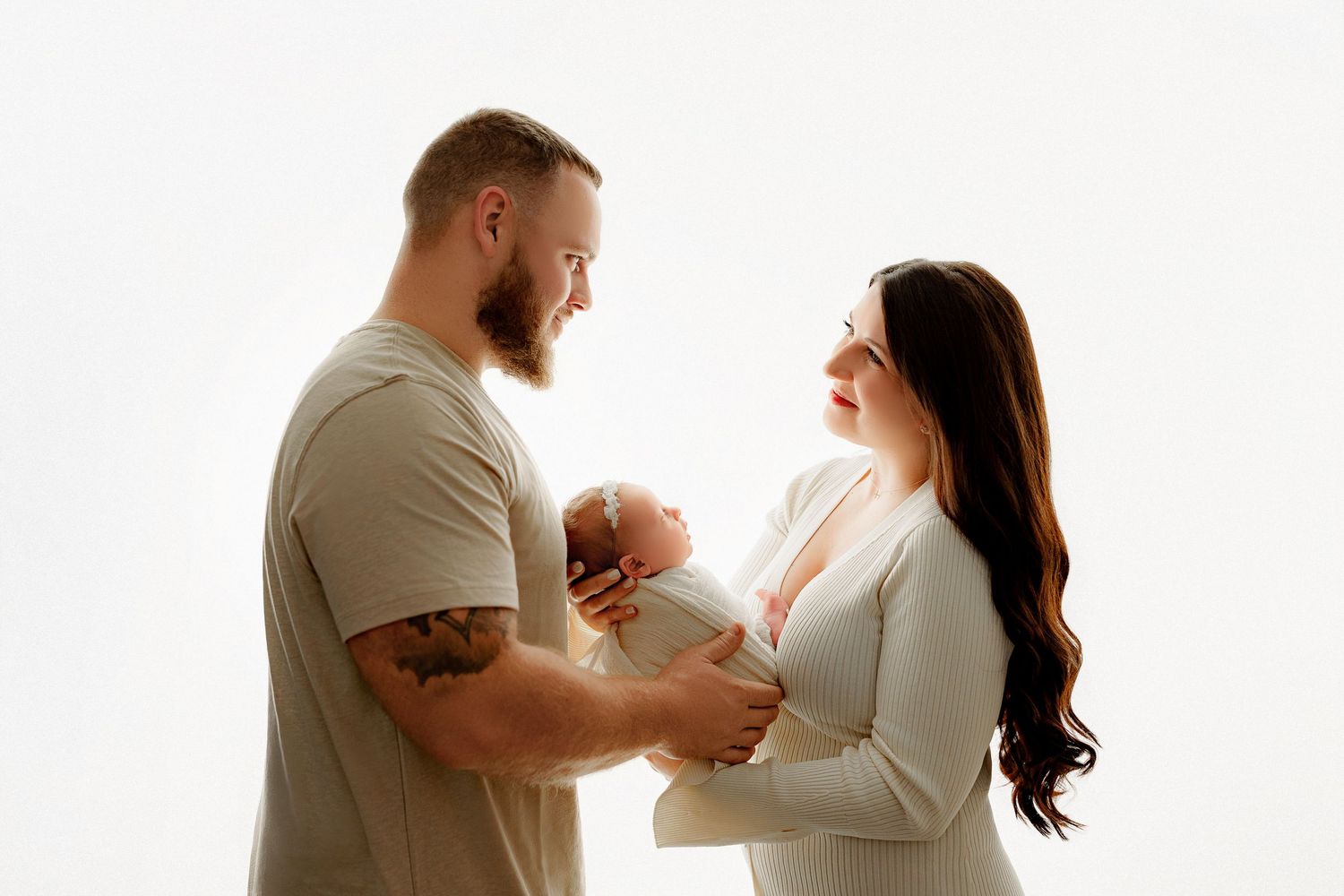 New parents holding baby girl swaddled during newborn photography session Indianapolis