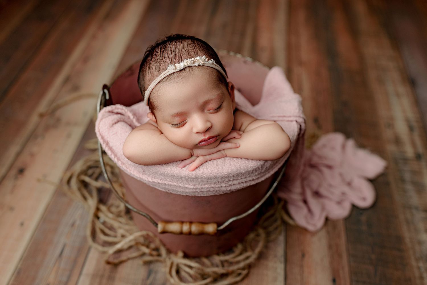Baby girl posed in pink bucket on wood background newborn session in Indianapolis Indiana