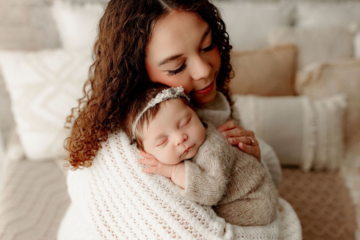 Mother dressed in neutrals holding sleeping baby girl in cozy Indianapolis newborn photography studio