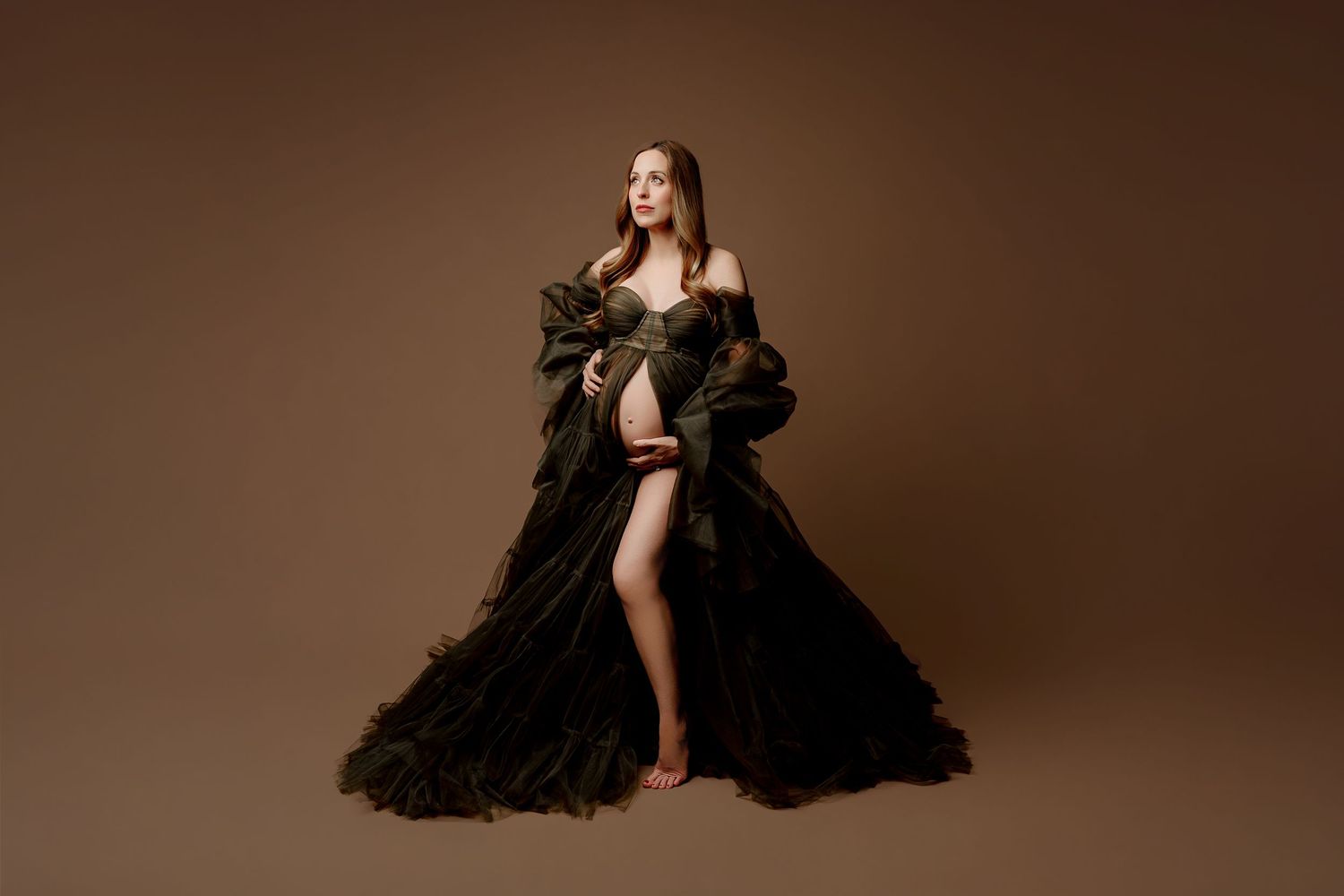 Pregnant woman in a flowing dark green gown in Indianapolis studio maternity photo shoot