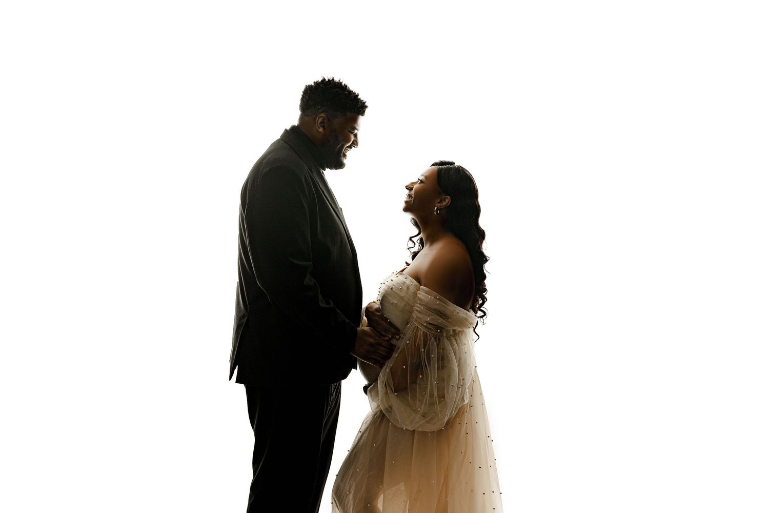 Silhouette of a couple facing each other against a white background. The woman, wearing a flowing dress, cradles her baby bump