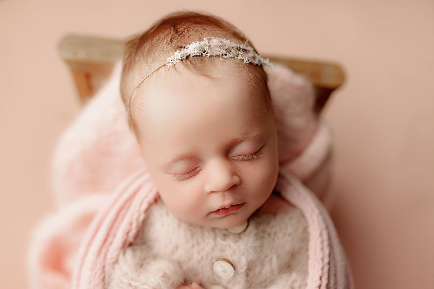 Baby girl in a soft pink outfit wrapped in a soft pink swaddle for a timeless newborn portrait indianapolis
