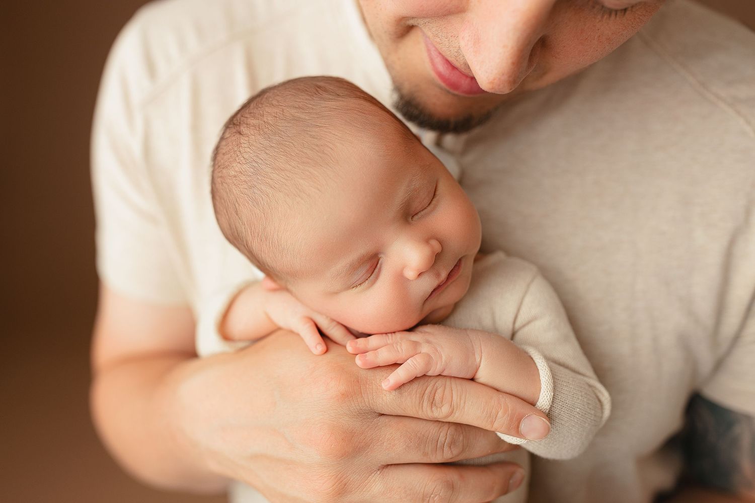A person gently holds a peacefully sleeping baby against their chest, conveying warmth and tenderness.