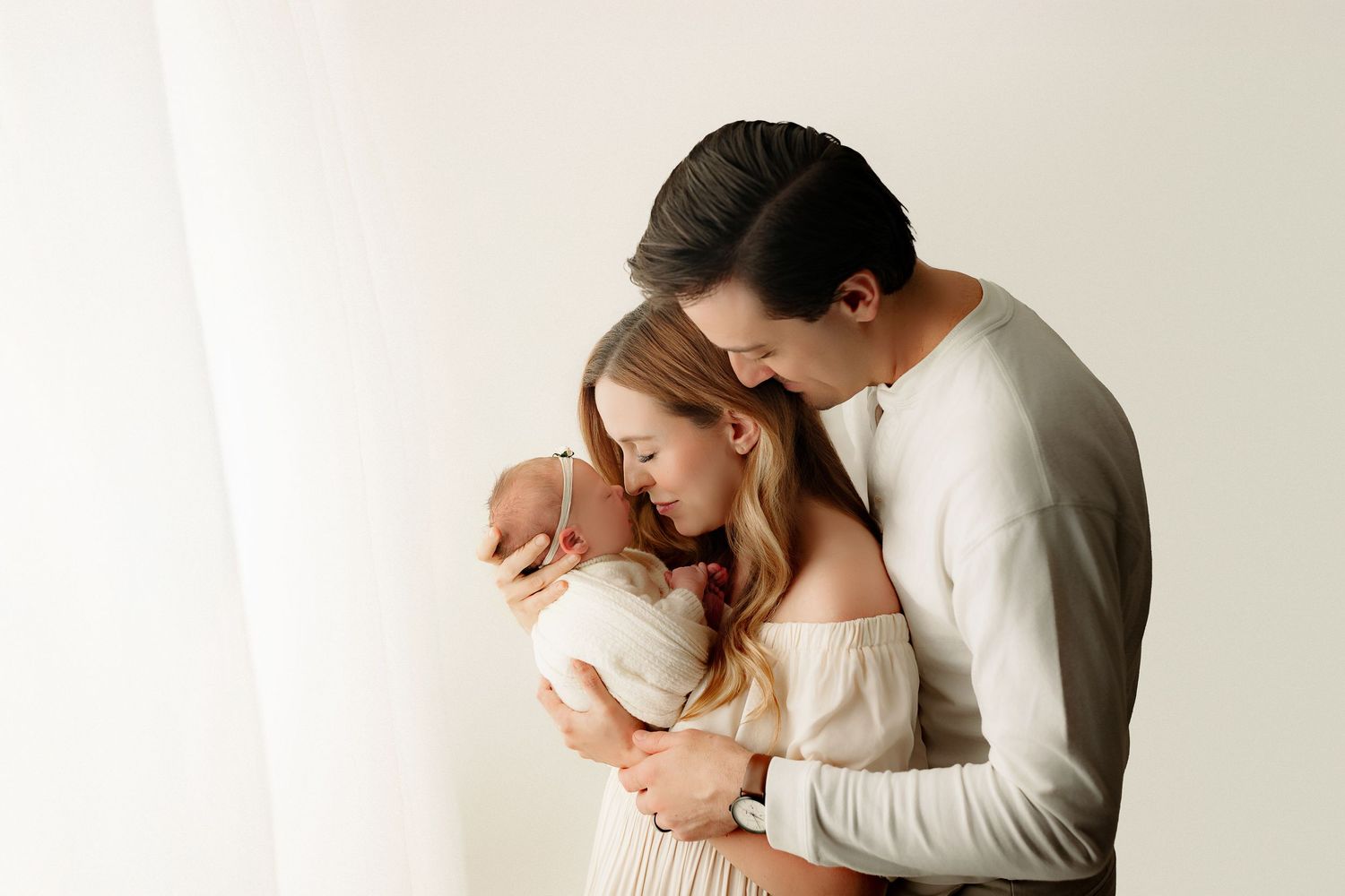 Parents holding newborn baby swaddled in cozy Indianapolis newborn photo studio