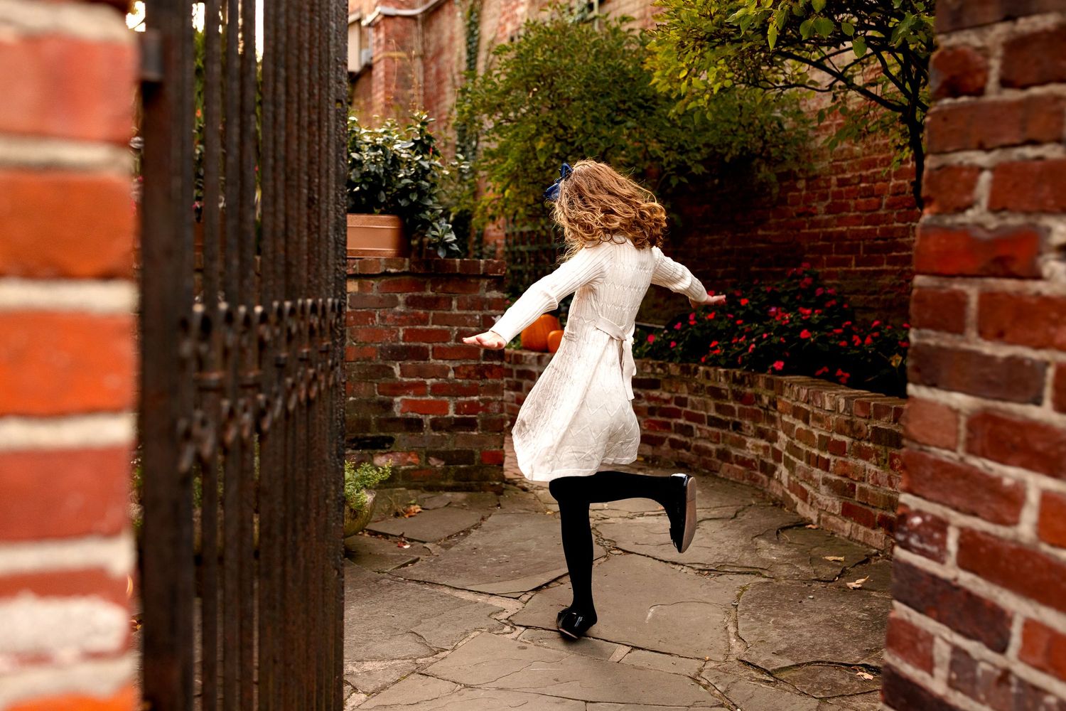 Fun child portrait of girl spinning in a brick courtyard with greenery in Zionsville, IN