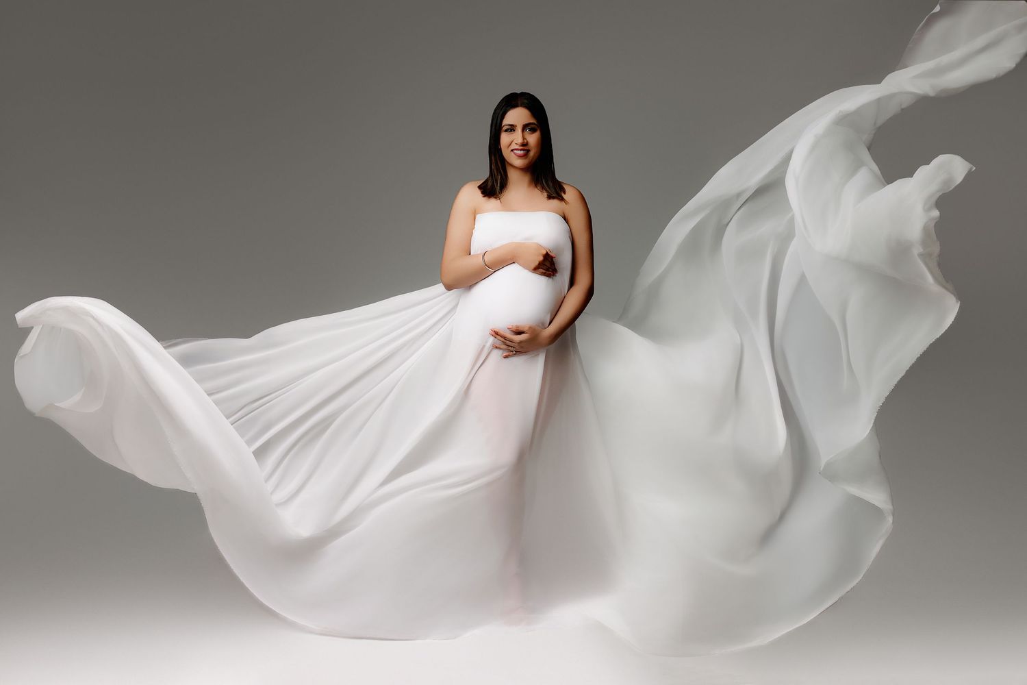 pregnant woman in white flowing fabric in indianapolis studio maternity session
