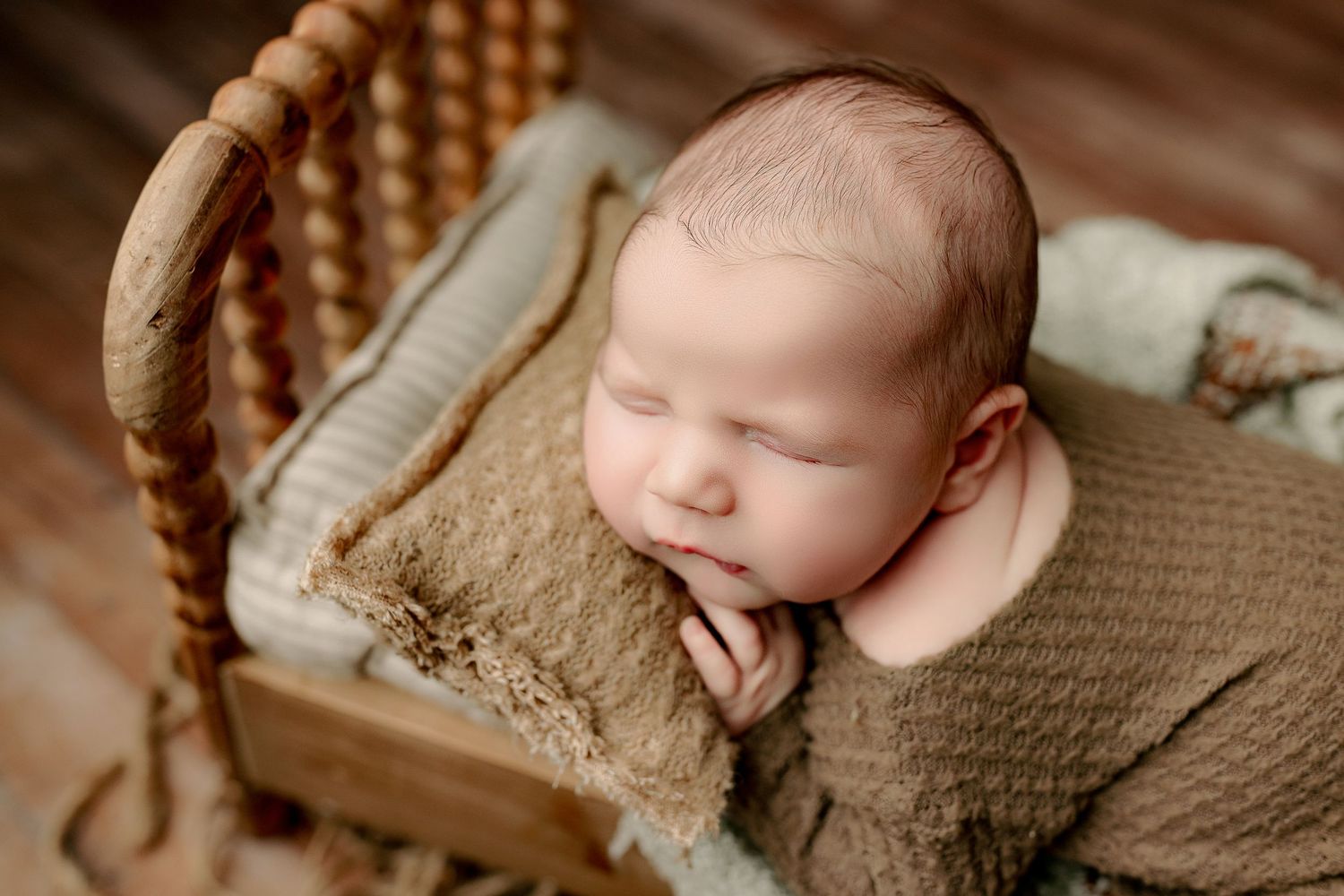Newborn baby boy sleeping on tiny bed during Indianapolis newborn photo session