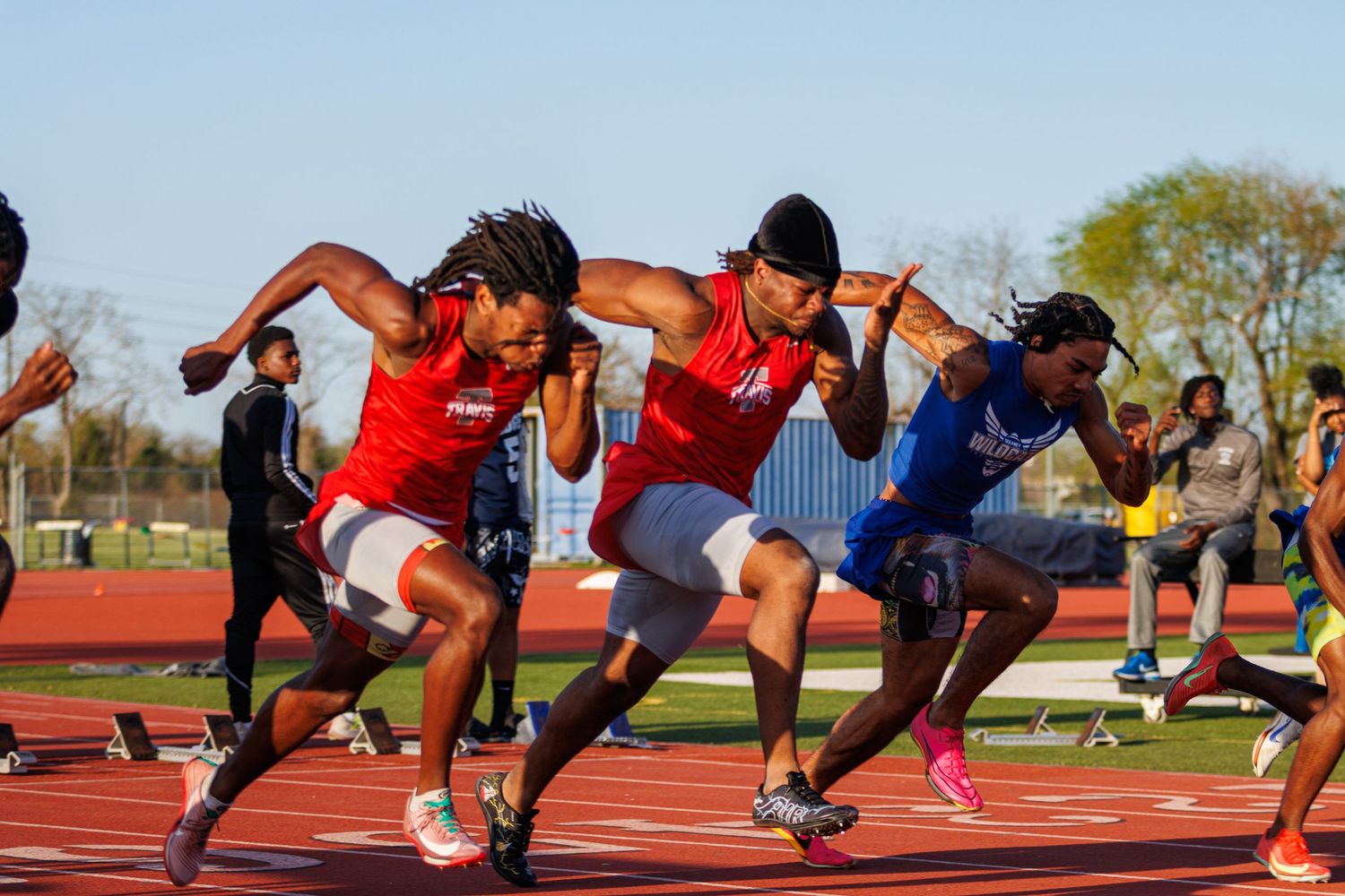 Travis High School sprinters bursting from starting blocks at beginning of race in Houston, TX.