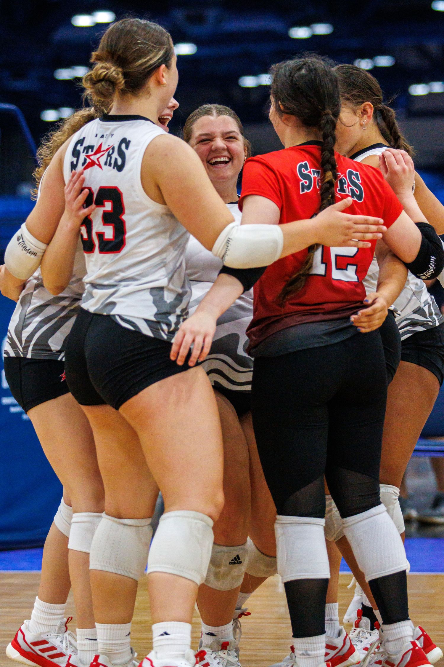Katy Stars 16U volleyball teammates celebrating together in a group huddle on the court in Houston, TX.