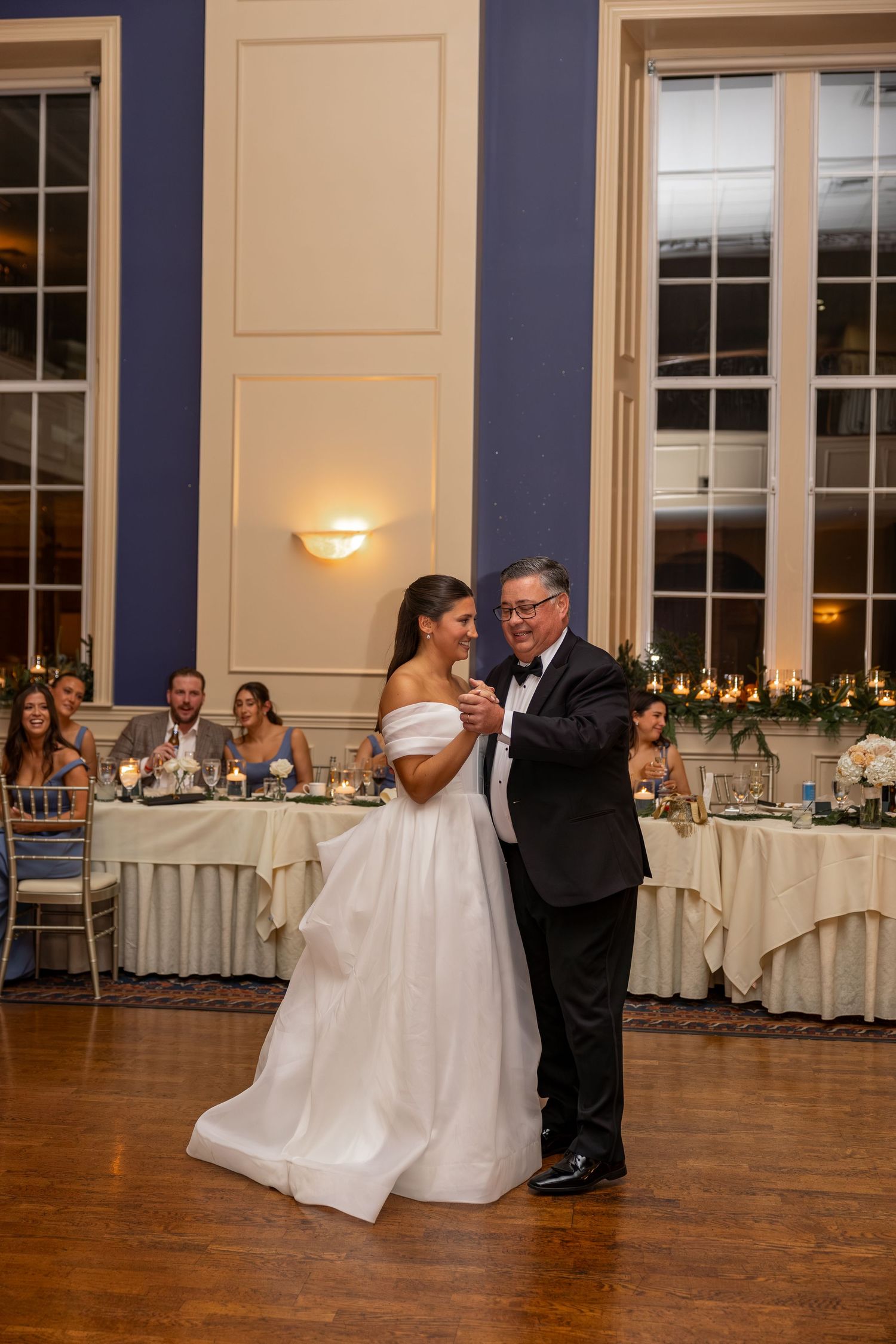Bride and groom sharing their first dance in an elegant ballroom with navy walls.