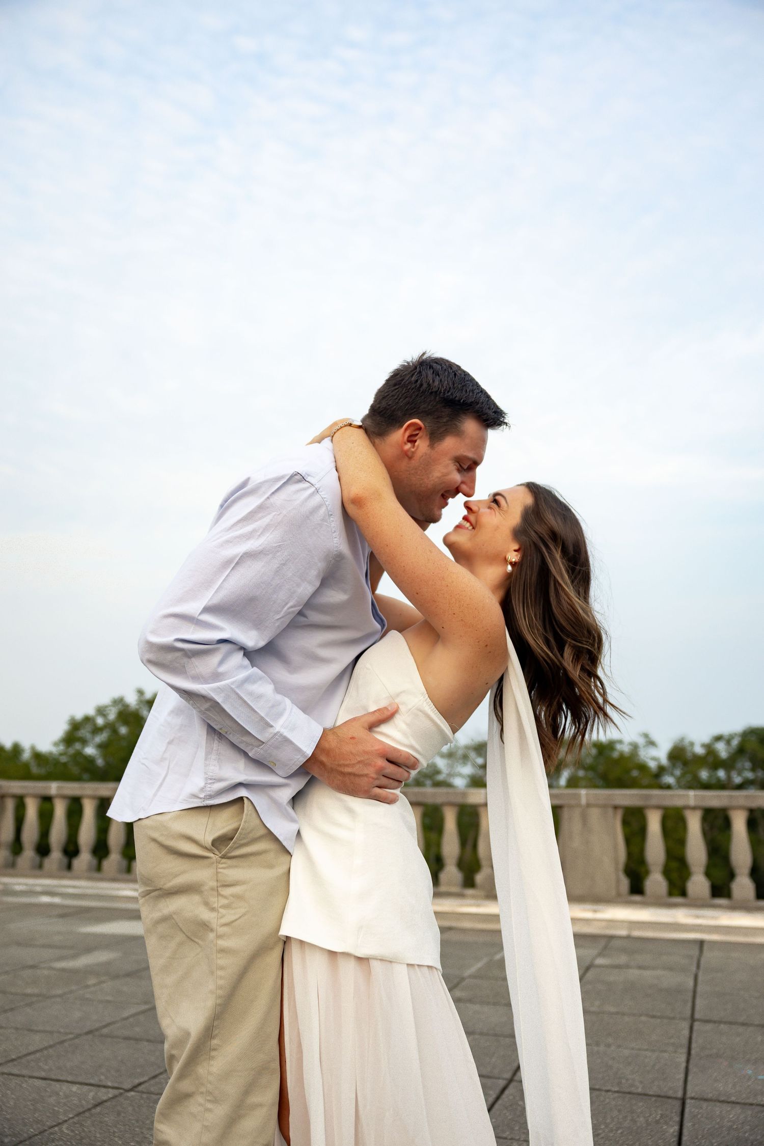 A romantic moment captured between a couple in white and blue outfits on a stone terrace.