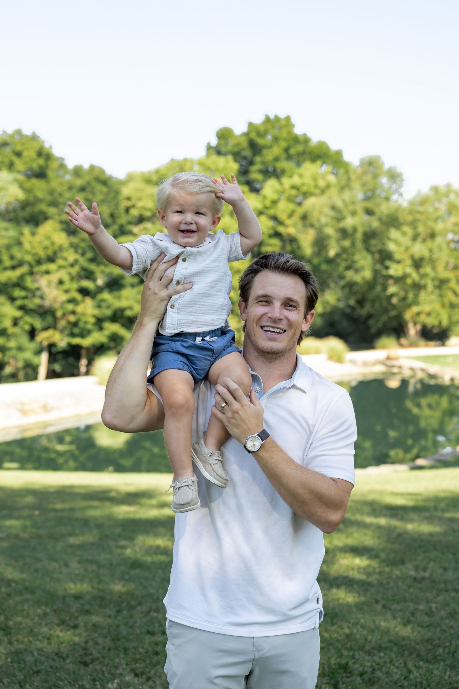 Playful outdoor moment between parent and baby on grassy field.