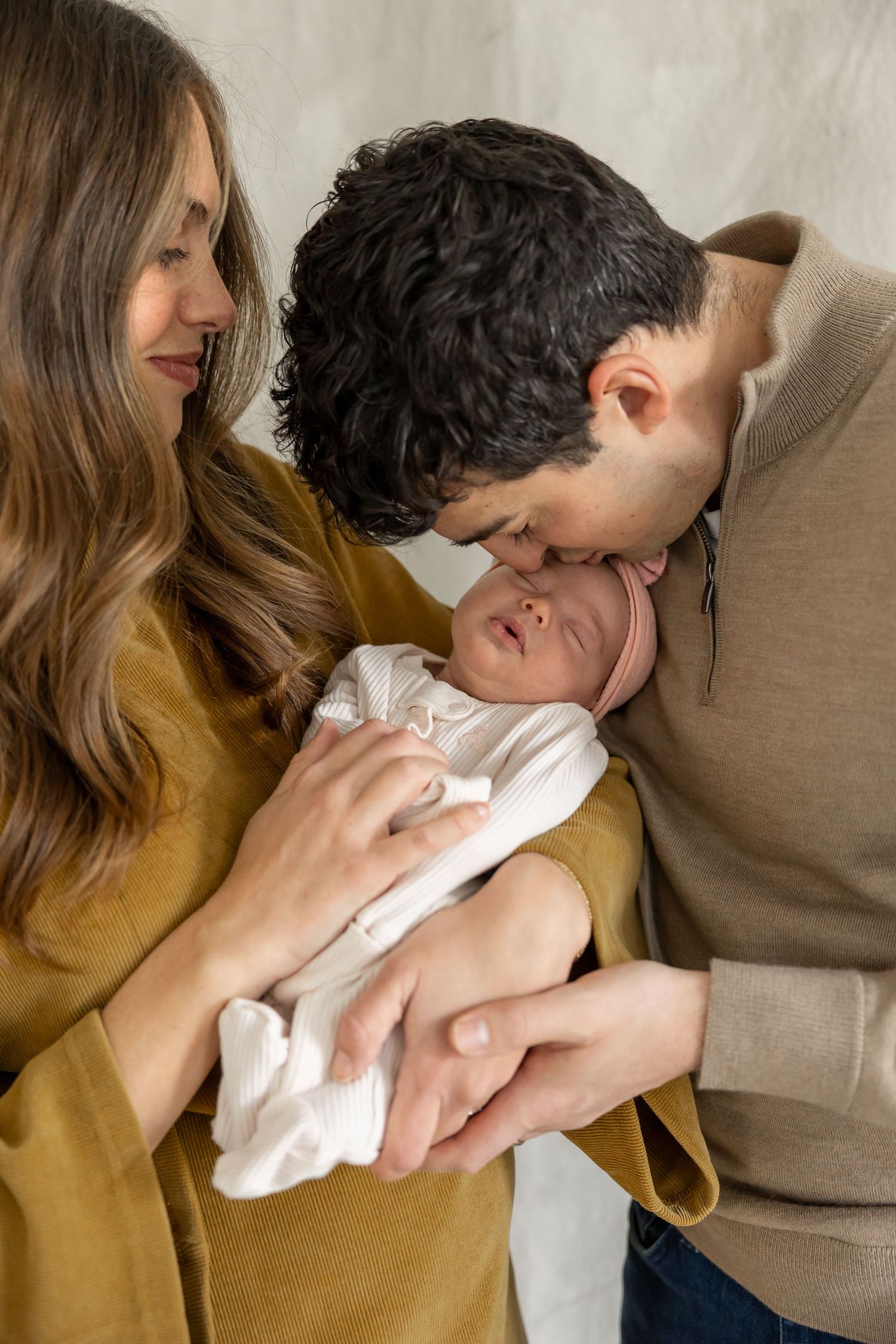 Intimate moments between parents and newborn baby in soft natural light.