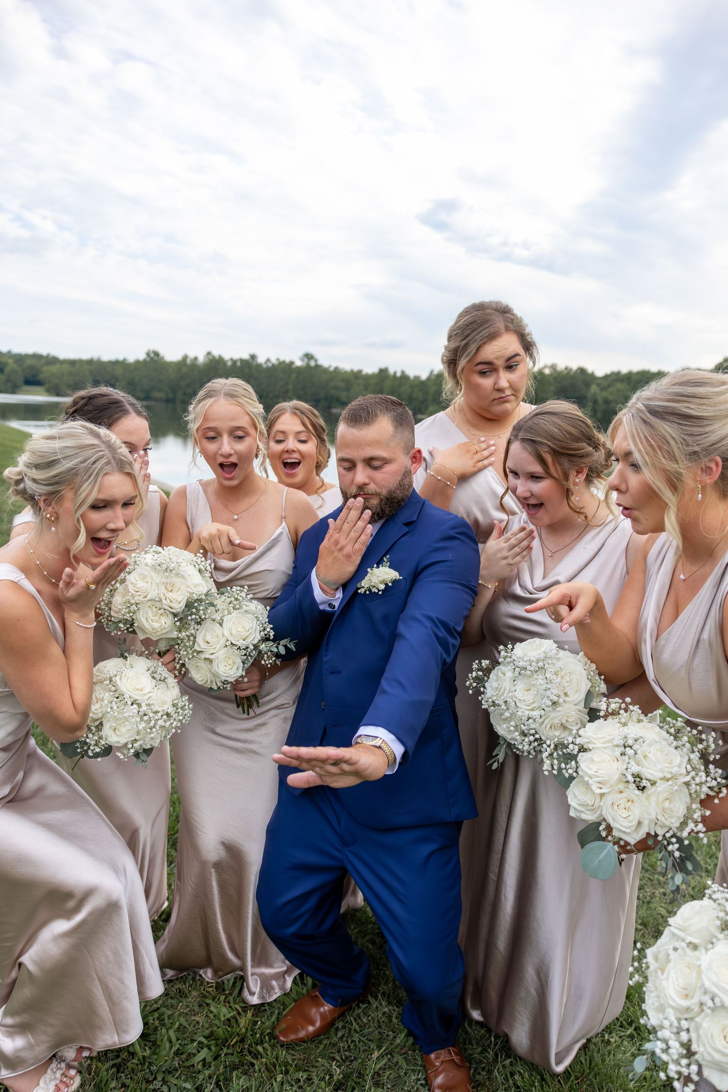 Candid moment of wedding party laughing together outdoors in blue and neutral tones.