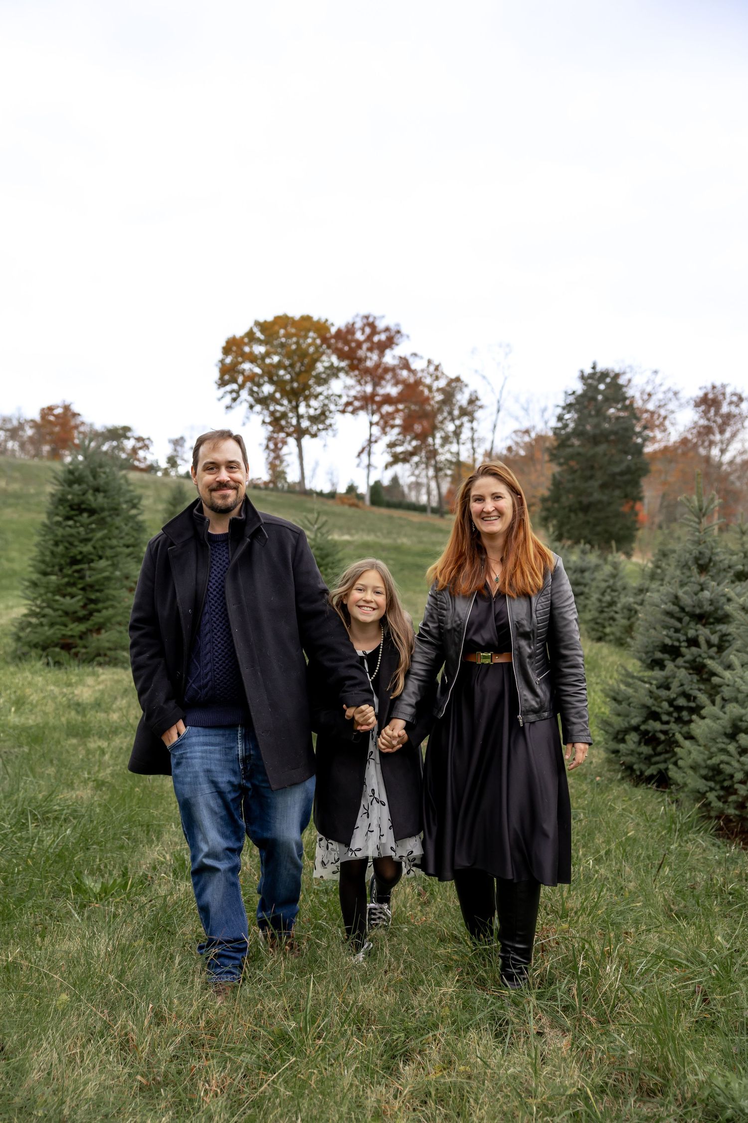 Family walking together on a grassy path wearing black jackets.