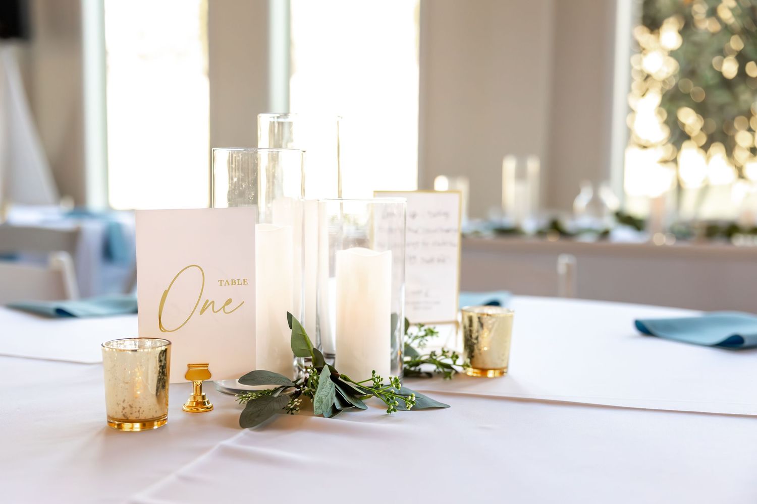 Minimalist white wedding reception table with simple decor and place settings.