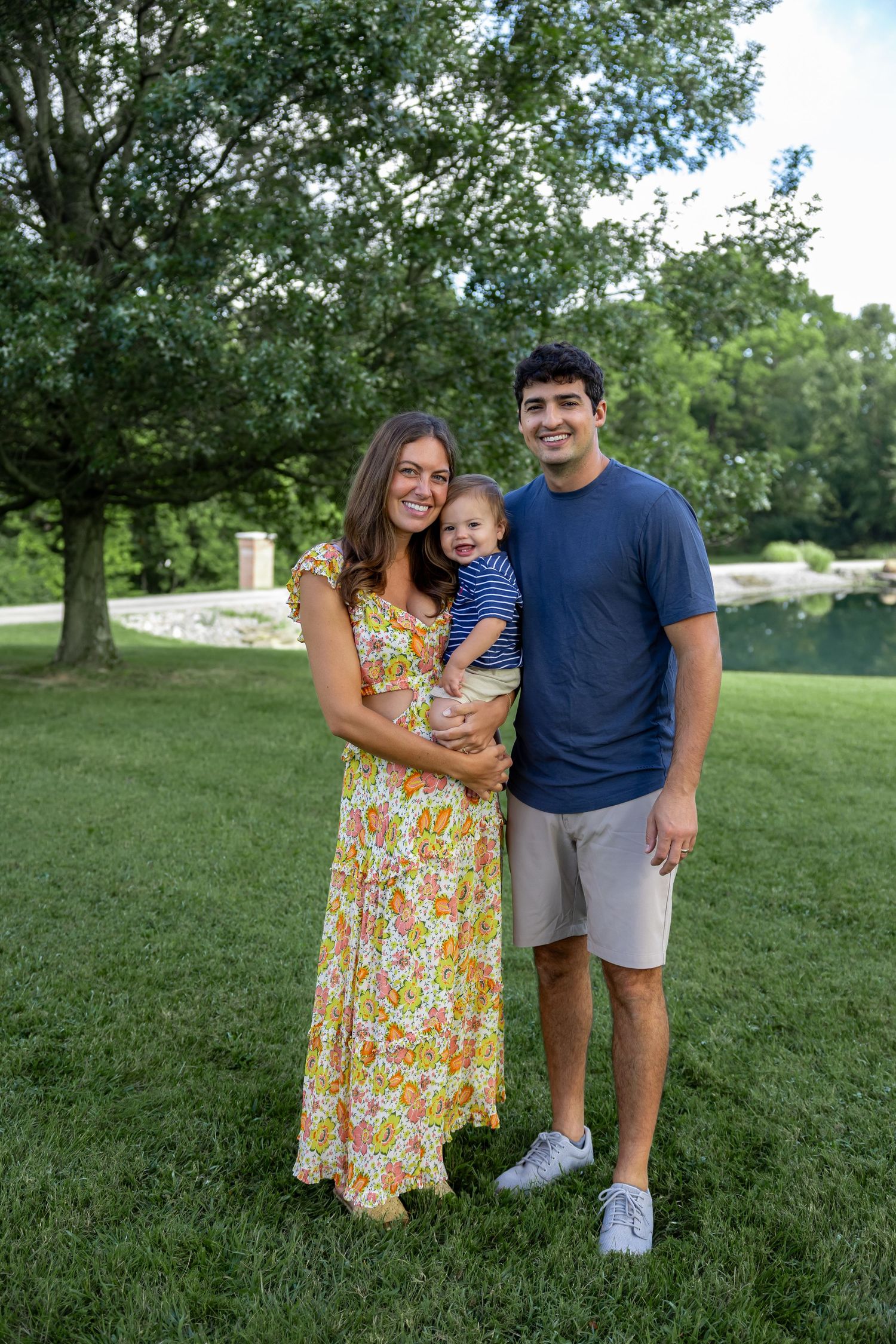 Family enjoying a sunny day outdoors in a park with trees and grass in the background.