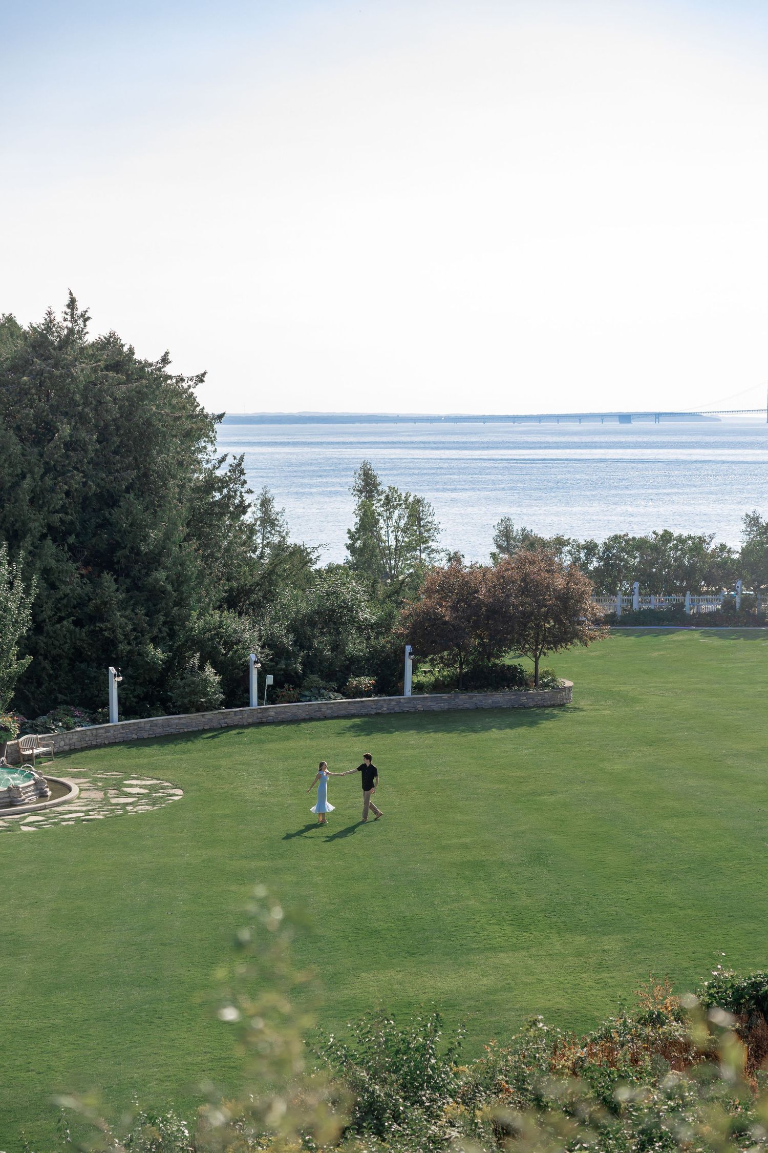 Scenic view of a vast green lawn overlooking the ocean with trees in the distance.