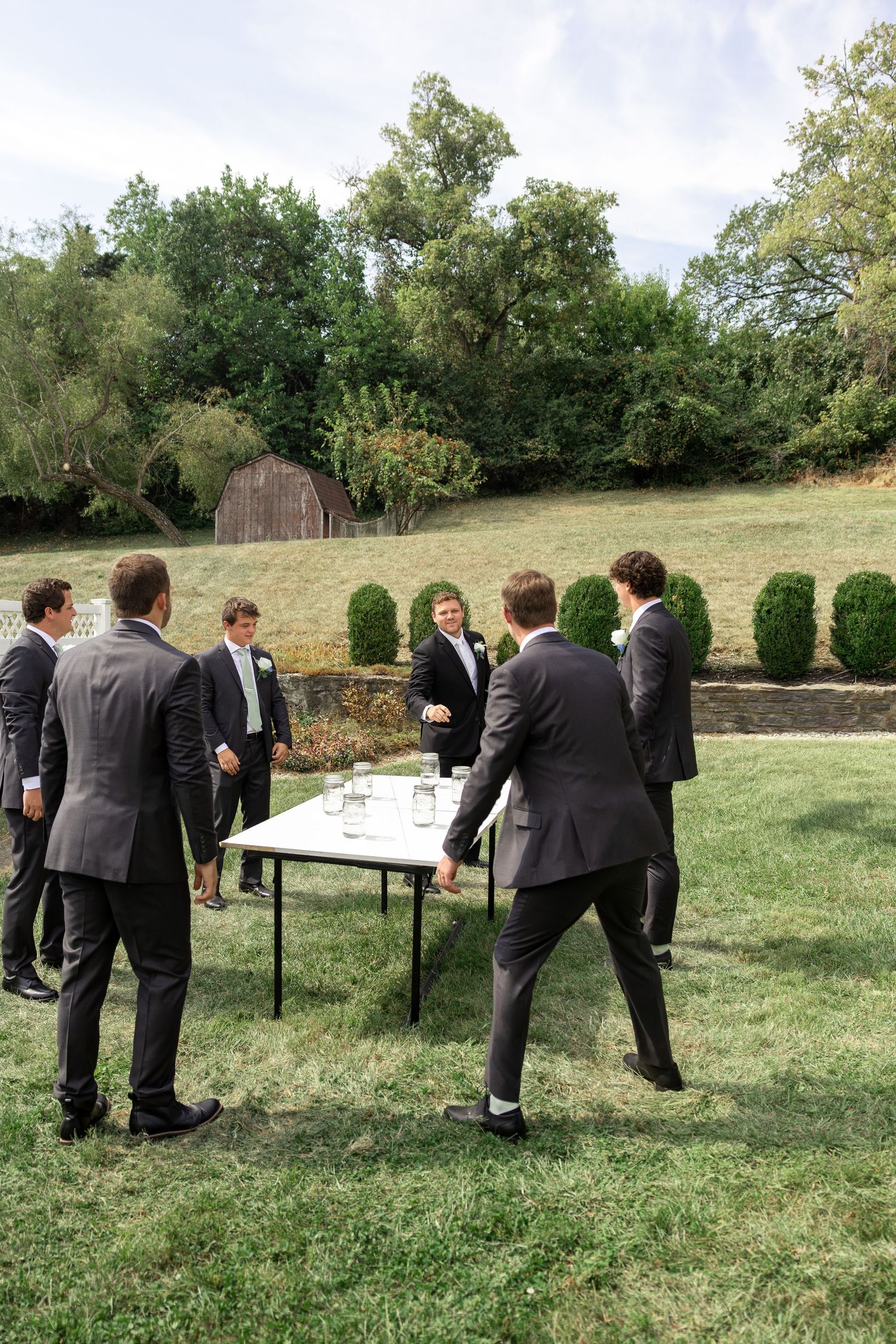 Group playing beer pong outdoors on tables set up on grass.