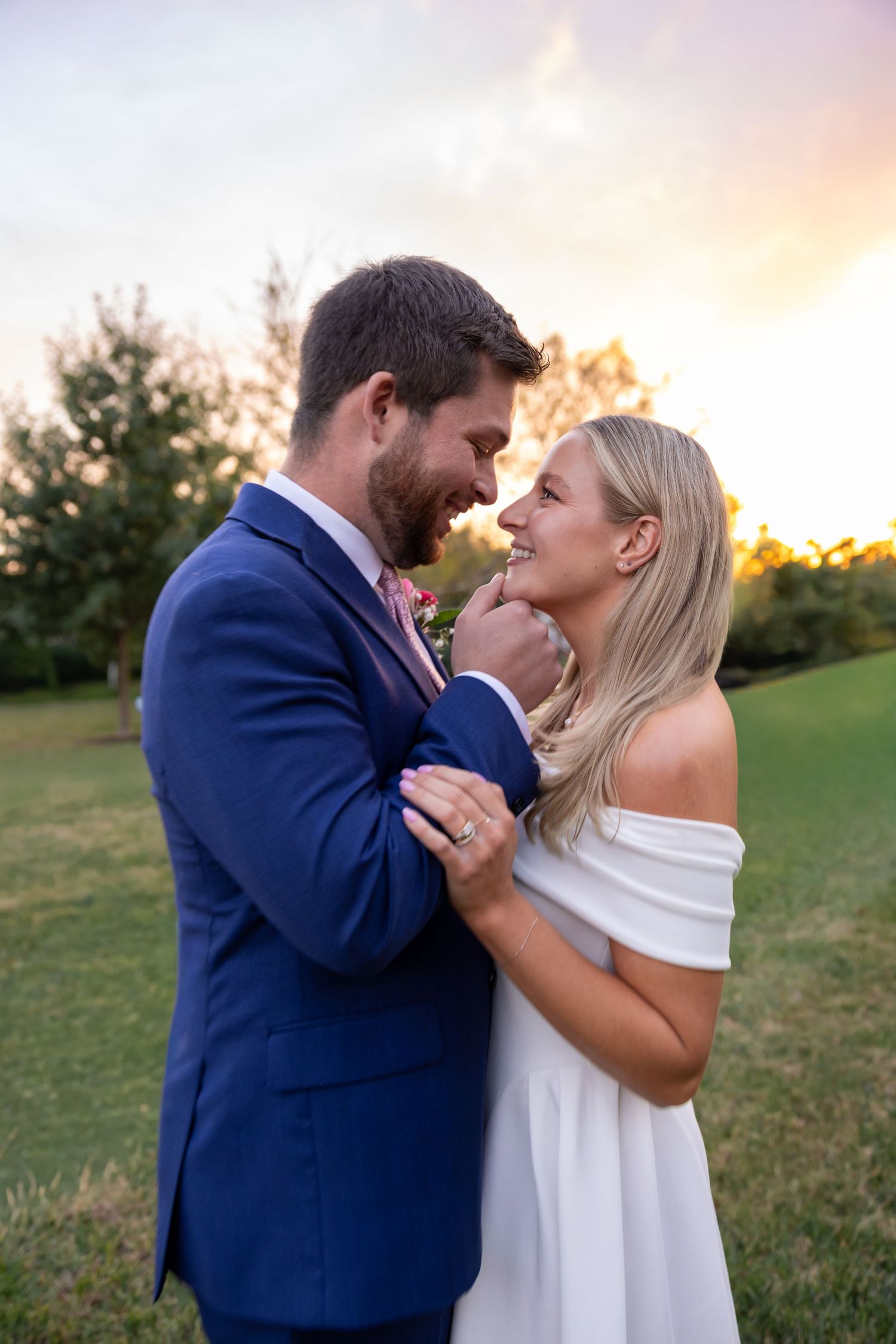 A couple shares an intimate moment at sunset in a grassy field.