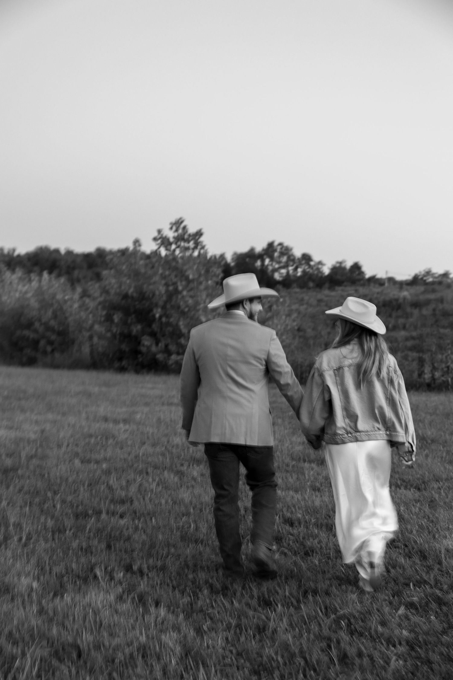 Black and white photo of two people walking together in a rural field.