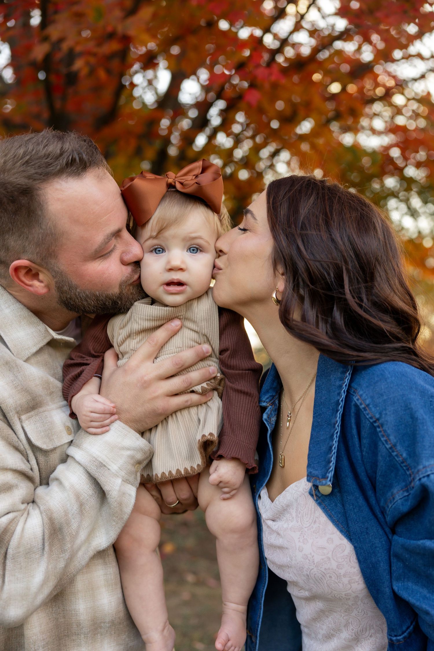 Family portrait session with fall foliage backdrop in warm autumn colors.