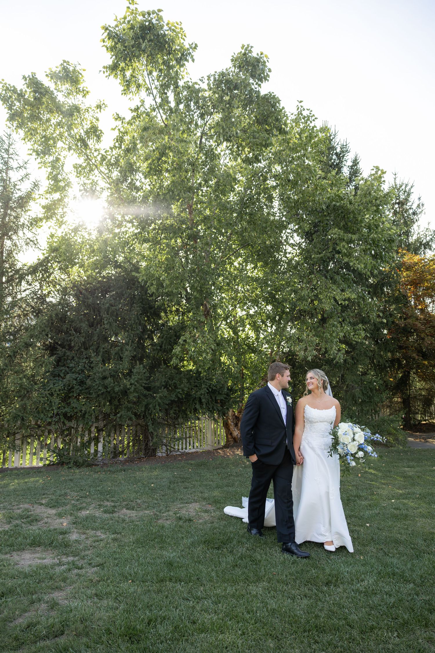 Outdoor wedding photo session on grassy hillside with natural backdrop.