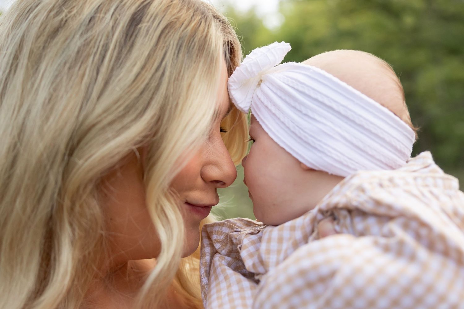 Parents share tender moments with their baby against a soft natural backdrop.
