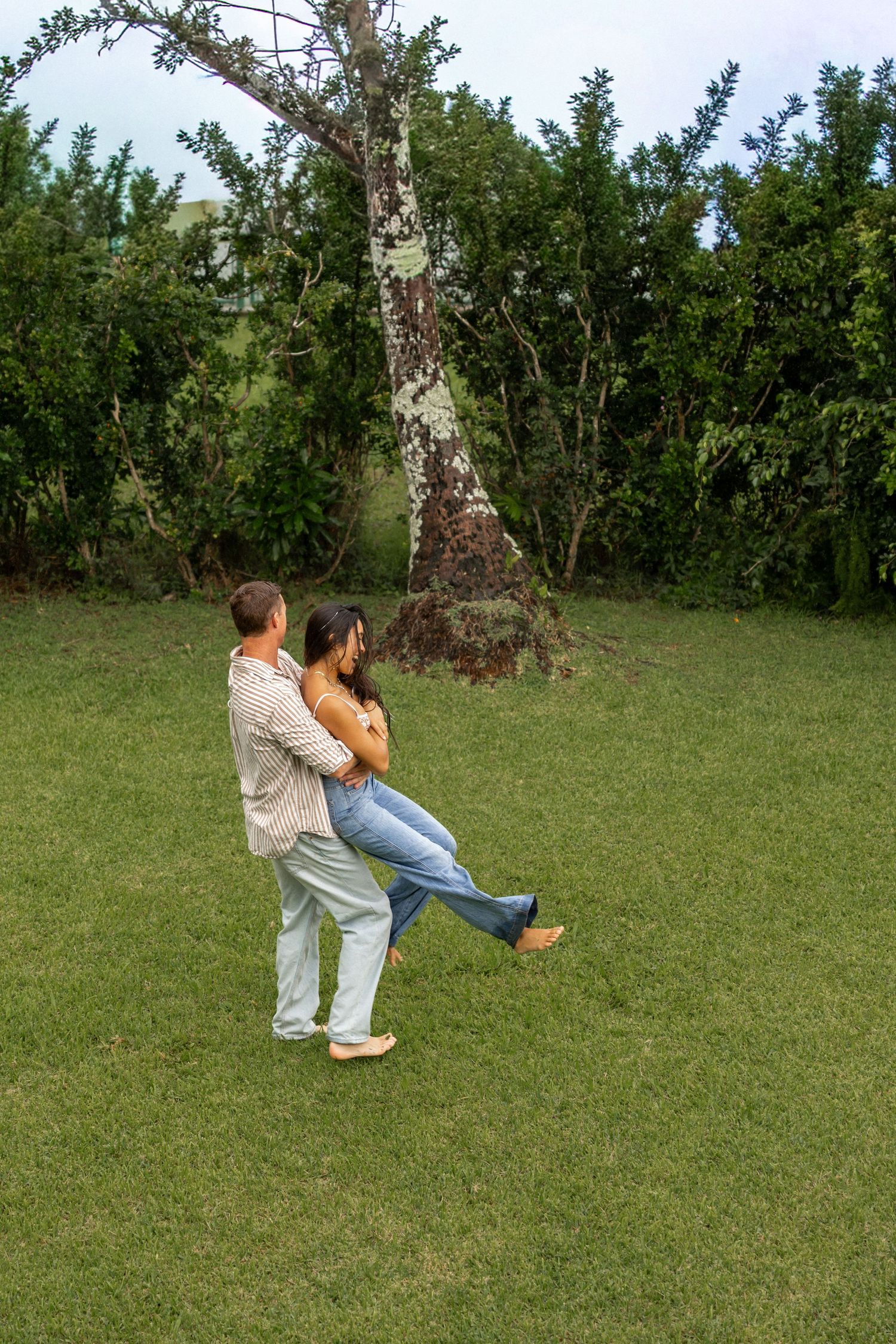 Playful couple dancing and spinning in a green field during summer.